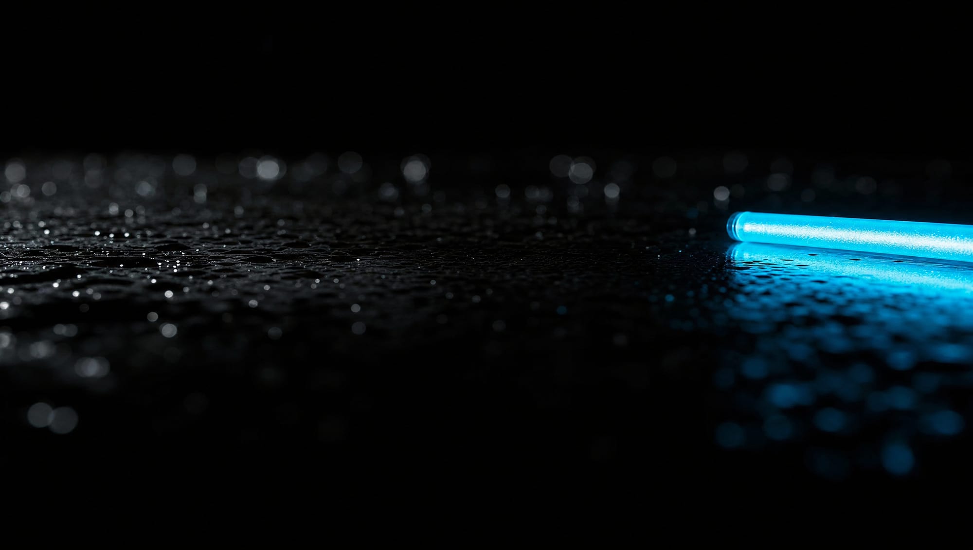 Wet black glass surface lit by one cyan light tube